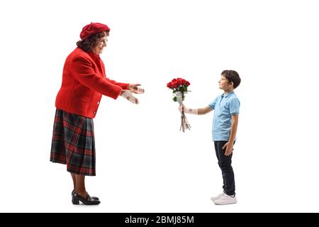 Photo de profil d'un petit-fils donnant un bouquet de roses rouges à sa grand-mère isolée sur fond blanc Banque D'Images