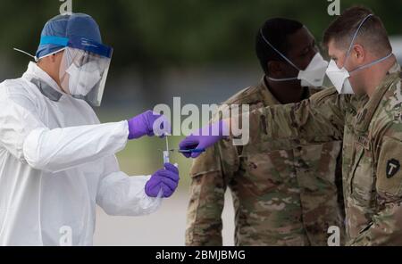 SPC. Nicholas Cisneros passe un écouvillon nasal prélevé sur un patient pendant que l'équipe mobile de test de la Garde nationale du Texas (MTT) teste le coronavirus dans une clinique de conduite gratuite dans la petite ville de Taylor, au centre du Texas. Banque D'Images