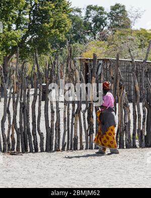 Femme avec des vêtements colorés et un serre-tête, marchant vers son village près du parc national d'Etosha en Namibie, Afrique Banque D'Images