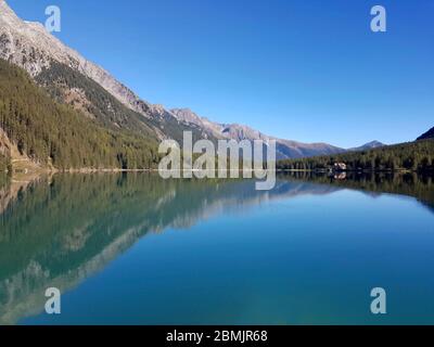 lac de montagne avec des eaux bleu pur, cabane agricole et bois vert sous un ciel clair Banque D'Images