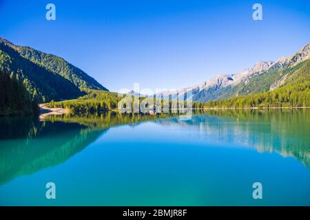 lac de montagne avec des eaux bleu pur, cabane agricole et bois vert sous un ciel clair Banque D'Images