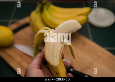 Banane pelée dans la main d'un homme Banque D'Images