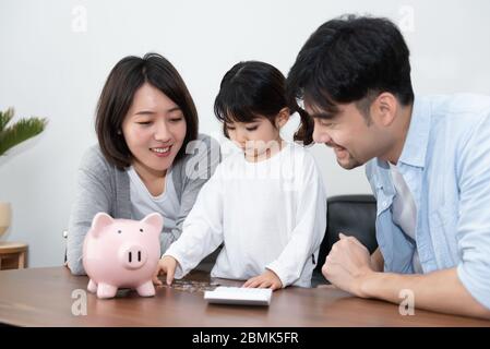 Les jeunes parents et mères asiatiques économisent de l'argent avec leur fille Banque D'Images