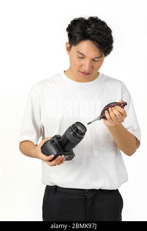 Un photographe asiatique nettoie l'appareil photo et l'objectif avec un appareil photo à soufflerie d'air pour la prise de vue de modèles de mode en studio. Banque D'Images