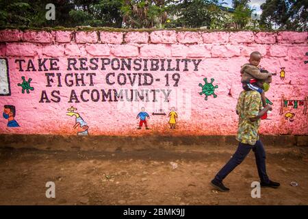 Nairobi, Kenya. 09e mai 2020. Un homme transportant son enfant passe devant un mur avec un graffiti pour sensibiliser le public au covid 19 pendant la pandémie du virus corona. Le Kenya a enregistré 649 cas confirmés, 207 cas de rétablissement et 30 décès dus à la maladie de Covid 19. Crédit : SOPA Images Limited/Alamy Live News Banque D'Images