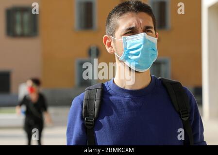 COVID-19 Homme social en distance dans la rue de la ville portant un masque chirurgical contre le virus SRAS-COV-2. Portrait de l'homme avec masque marche respectant social dista Banque D'Images