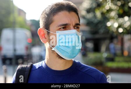 COVID-19 coronavirus pandémique gros plan de l'homme dans la rue en ville portant un masque chirurgical pour la propagation de la maladie du coronavirus 2019. Portrait de l'homme avec fac Banque D'Images