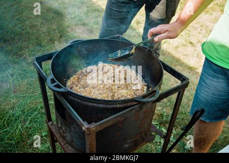 Pilaf cuisson dans le chou-fleur sur feu en plein air série. Les morceaux de viande d'agneau et d'oignon sont frits dans l'huile bouillante dans la poêle au feu. Étape par étape 3 processus de co Banque D'Images