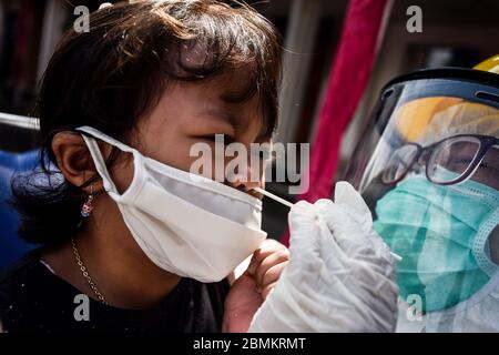 Bandung, Indonésie. 10 mai 2020. Un travailleur de la santé, portant des combinaisons de protection, effectue une masse d'essai par écouvillonnage sur un enfant à Bandung, West Java, Indonésie, le 10 mai 2020. Des pays du monde entier prennent des mesures pour enrayer la propagation du coronavirus du COV-SRAS-2, qui cause la maladie COVID-19. (Photo par Agvi Firdaus/INA photo Agency/ Credit: SIPA USA/Alay Live News Banque D'Images