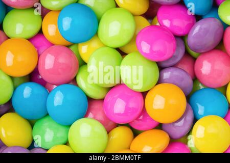 Pile de chocolats bonbons sucrés colorés sur papier blanc couché colorés en arrière-plan de collecte. Banque D'Images