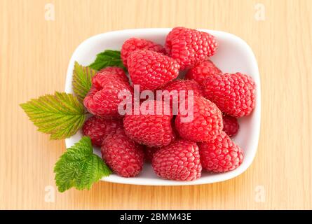 Gros plan de framboises rouges, mûres et sucrées dans un bol blanc, Royaume-Uni. Banque D'Images