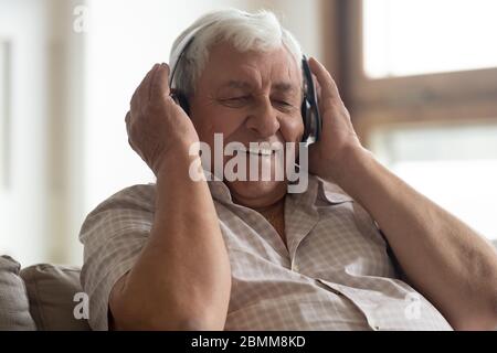 Homme de haut niveau souriant écoutez de la musique dans un casque sans fil Banque D'Images