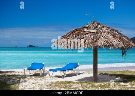 Deux chaises de plage et un parasol fixe sur une plage des caraïbes. Banque D'Images