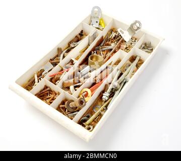 bac de rangement en plastique blanc rempli de morceaux et de mèches de handyman. seaux, vis, écrous et boulons. studio tourné en blanc Banque D'Images