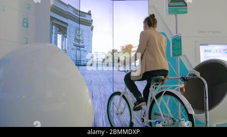 Moscou, Russie - le 30 juillet 2018 : Exposition de ville intelligente. Jeune femme à l'aide d'interactive location simulator machine en avant du grand écran à la technique Banque D'Images