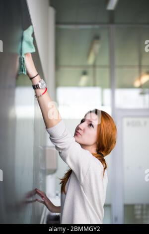 Jeune étudiant écrit sur le tableau/blackboard pendant un cours de mathématiques. Banque D'Images