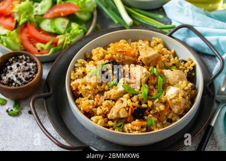 Pilaf bulgur. Concept de saine alimentation. Boulgour avec poulet, légumes et pruneaux sur un comptoir en pierre grise ou en ardoise. Banque D'Images