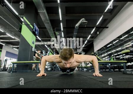 Portrait d'un homme beau faisant des exercices de poussée dans la salle de fitness Banque D'Images