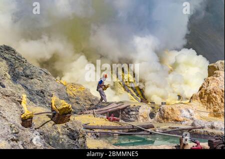 Kawah Ijen, Java, Indonésie - 6 août 2010 : mineur de soufre transportant un bloc de soufre au volcan Kawah Ijen, à Java-est, Indonésie. Banque D'Images