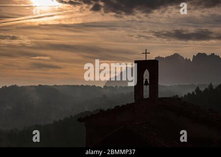 Matin brumeux à Montserrat et une petite silhouette d'église de Sant Salvador de Guardiola Banque D'Images