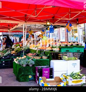 Marché extérieur de Hogh Street négociant vendre des légumes frais sains sous UNE canopée rouge Banque D'Images