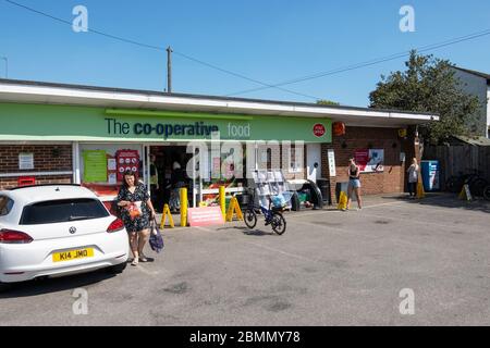 Stone, Buckinghamshire, Royaume-Uni. 9 mai 2020. Magasin de proximité de cuisine coopérative Village. File d'attente de la boutique en observant les distances sociales comme demandé par avis. Membre du personnel de l'atelier debout à l'entrée et contrôlant la petite file d'attente. Une femme âgée entre dans un magasin passant membre du personnel seulement par quelques pieds, loin moins de 2m, pas de distance sociale. Voir l'image 2BMMY71 pour la situation avant que la femme âgée entre dans le magasin. Crédit : Stephen Bell/Alay Banque D'Images