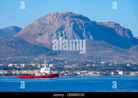 Journée d'été ensoleillée dans le golfe de Corinthe. Un remorqueur au fond d'une petite ville sur une rive montagneuse. Vue de l'eau Banque D'Images