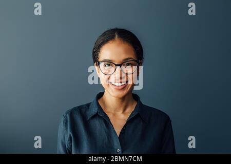 Portrait d'une femme d'affaires qui porte des lunettes et regarde l'appareil photo dans le salon Banque D'Images