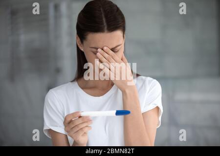Contrarié femme regardant le test de grossesse mauvais résultat se sent déçu Banque D'Images