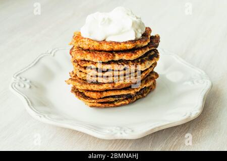 Beignets de courgettes de légumes empiler la crème aigre servie sur la plaque blanche de près. Banque D'Images