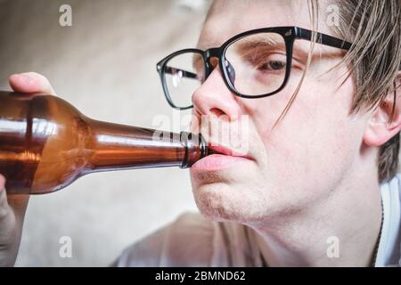 Un homme déprimé boit de l'alcool à cause de la douleur. Gros plan. Banque D'Images