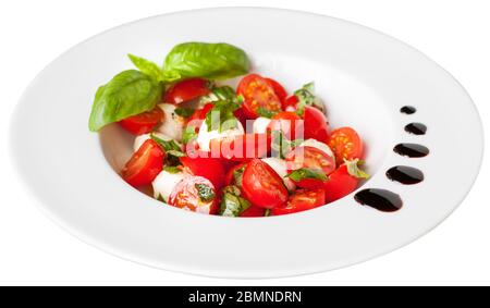 Salade fraîche et savoureuse avec mozzarella, tomates cerises et feuilles de basilic. Isolé sur fond blanc. Banque D'Images