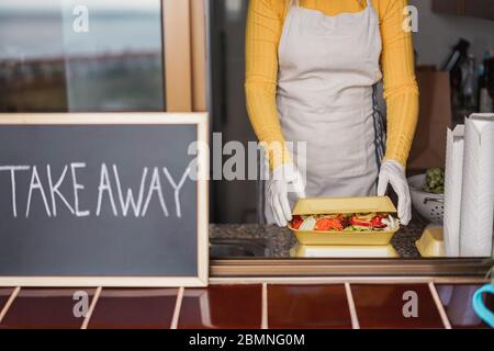 Jeune femme préparant des plats sains à emporter dans le restaurant pendant l'éclosion de Coronavirus - travailleur dans la cuisine cuisine cuisine cuisine cuisine végétarienne pour onl Banque D'Images