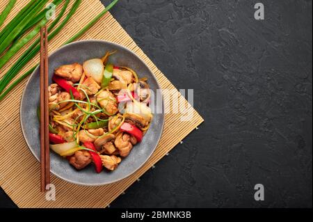 Poulet au gingembre thaïlandais ou lit King Size Gai Pad dans un bol gris sur fond d'ardoise noire. Gai Pad King est un plat de cuisine de Thaïlande avec viande de poulet, des bandelettes de gingembre, onio Banque D'Images