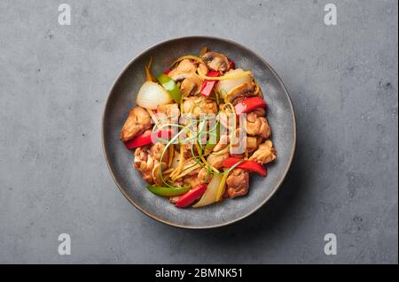 Poulet au gingembre thaïlandais ou lit King Size Gai Pad dans un bol gris mat sur fond de béton. Gai Pad King est un plat de cuisine thaïlandais avec viande de poulet, des bandelettes de gingembre, o Banque D'Images