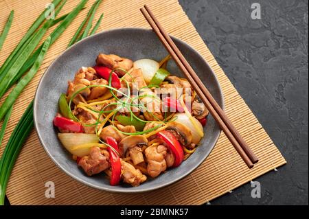 Poulet au gingembre thaïlandais ou lit King Size Gai Pad dans un bol gris sur fond d'ardoise noire. Gai Pad King est un plat de cuisine de Thaïlande avec viande de poulet, des bandelettes de gingembre, onio Banque D'Images