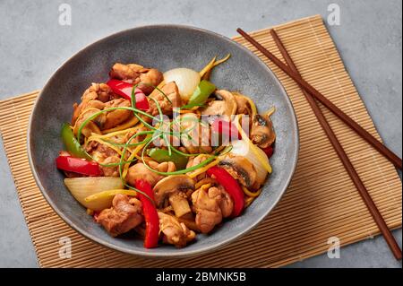 Poulet au gingembre thaïlandais ou lit King Size Gai Pad dans un bol gris mat sur fond de béton. Gai Pad King est un plat de cuisine thaïlandais avec viande de poulet, des bandelettes de gingembre, o Banque D'Images