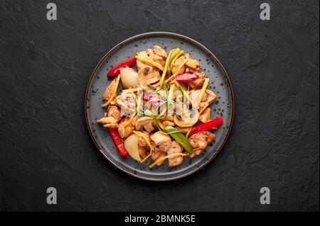 Poulet au gingembre thaïlandais ou lit King Size Gai Pad dans une assiette sombre sur fond d'ardoise noire. Gai Pad King est un plat de cuisine de Thaïlande avec viande de poulet, des lanières de gingembre, des oni Banque D'Images