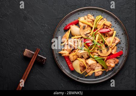 Poulet au gingembre thaïlandais ou lit King Size Gai Pad dans une assiette sombre sur fond d'ardoise noire. Gai Pad King est un plat de cuisine de Thaïlande avec viande de poulet, des lanières de gingembre, des oni Banque D'Images