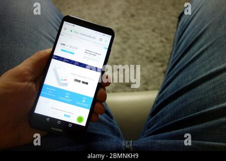 Homme tenant le smartphone Huawei avec le site Web d'échange de crypto-monnaies Huobi affiché. Concept de commerce en ligne Banque D'Images