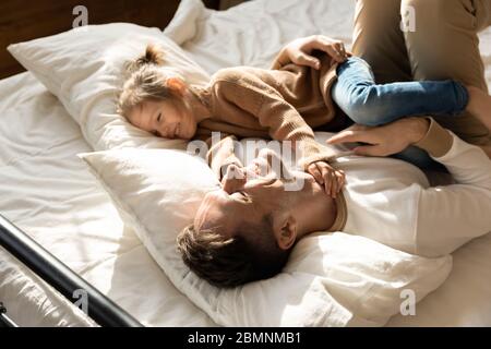 Un père heureux et une petite fille se détendent dans un lit confortable Banque D'Images