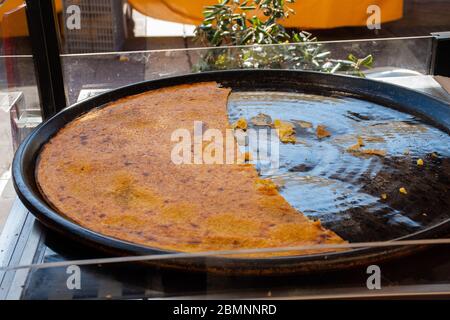 Grande assiette de Farinata ou Cecina ou Torta di ceci mince crêpe de crêpe de farine de pois chiches originaire de Gênes cuite dans un four à bois, soca Banque D'Images