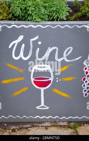 Vin signé à la main et dessin simple d'un verre de vin avec du vin rouge et du raisin bleu. Des publicités originales attirent les gens pour acheter du vin. Photo verticale. Banque D'Images