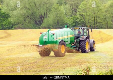 Un agriculteur qui épandre du lisier sur un champ de ferme conduit un tracteur John Deere 6930 dans la campagne du Cheshire en Angleterre Banque D'Images