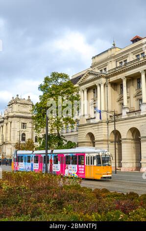 Budapest, Hongrie - 6 novembre 2019 : tramway jaune avec une publicité colorée devant le bâtiment du ministère de l'Agriculture. Musée d'Ethnographie en arrière-plan. Place Kossuth dans le centre-ville. Banque D'Images