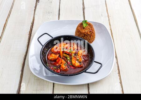 Crevettes à la sauce tomate dans une casserole. Garnir, riz aux herbes. Banque D'Images