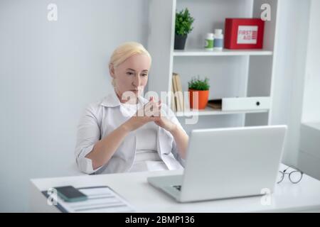 Un médecin blond d'âge moyen, assis à son bureau et qui a l'air attentionné Banque D'Images