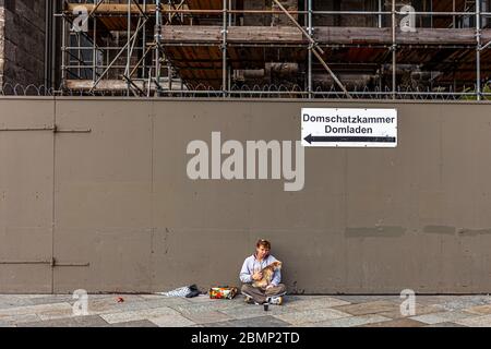 Mendiant à la cathédrale de Cologne, Allemagne. Le panneau indique la salle du Trésor Banque D'Images