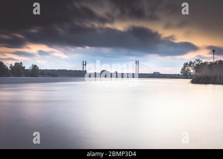 Pont de type télécâblé sur une rivière hollandaise près de la ville de Kampen Overijssel avec un coucher de soleil nuageux Banque D'Images