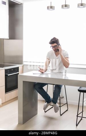 Photo de jeunes hommes d'affaires concentrés travaillant à l'intérieur. En vous épargnant les notes en parlant par téléphone portable. Banque D'Images